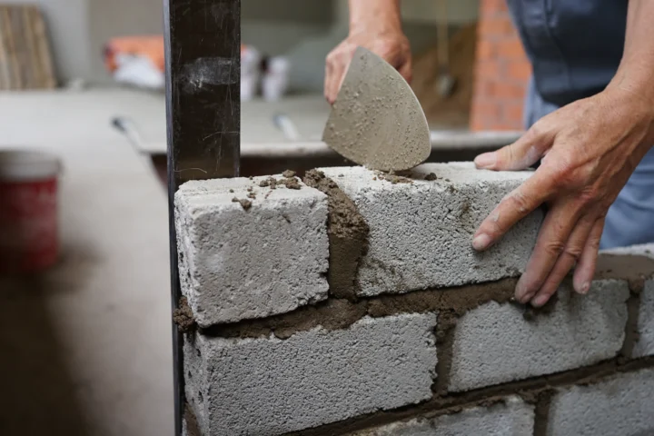 Artisan appliquant du mortier sur un mur de briques