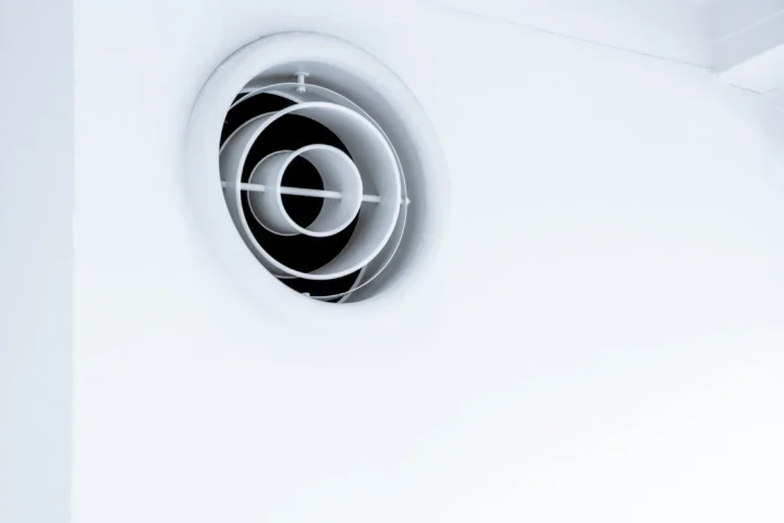Bouche d'aération ronde blanche fixée sur un mur blanc