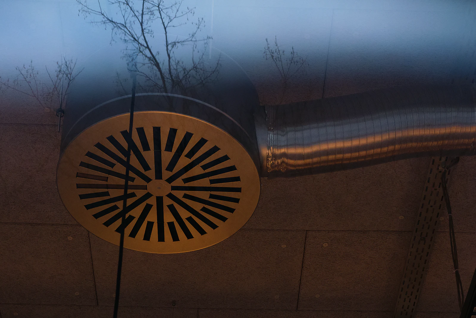 Bouche métallique circulaire raccordée à une gaine de ventilation apparente