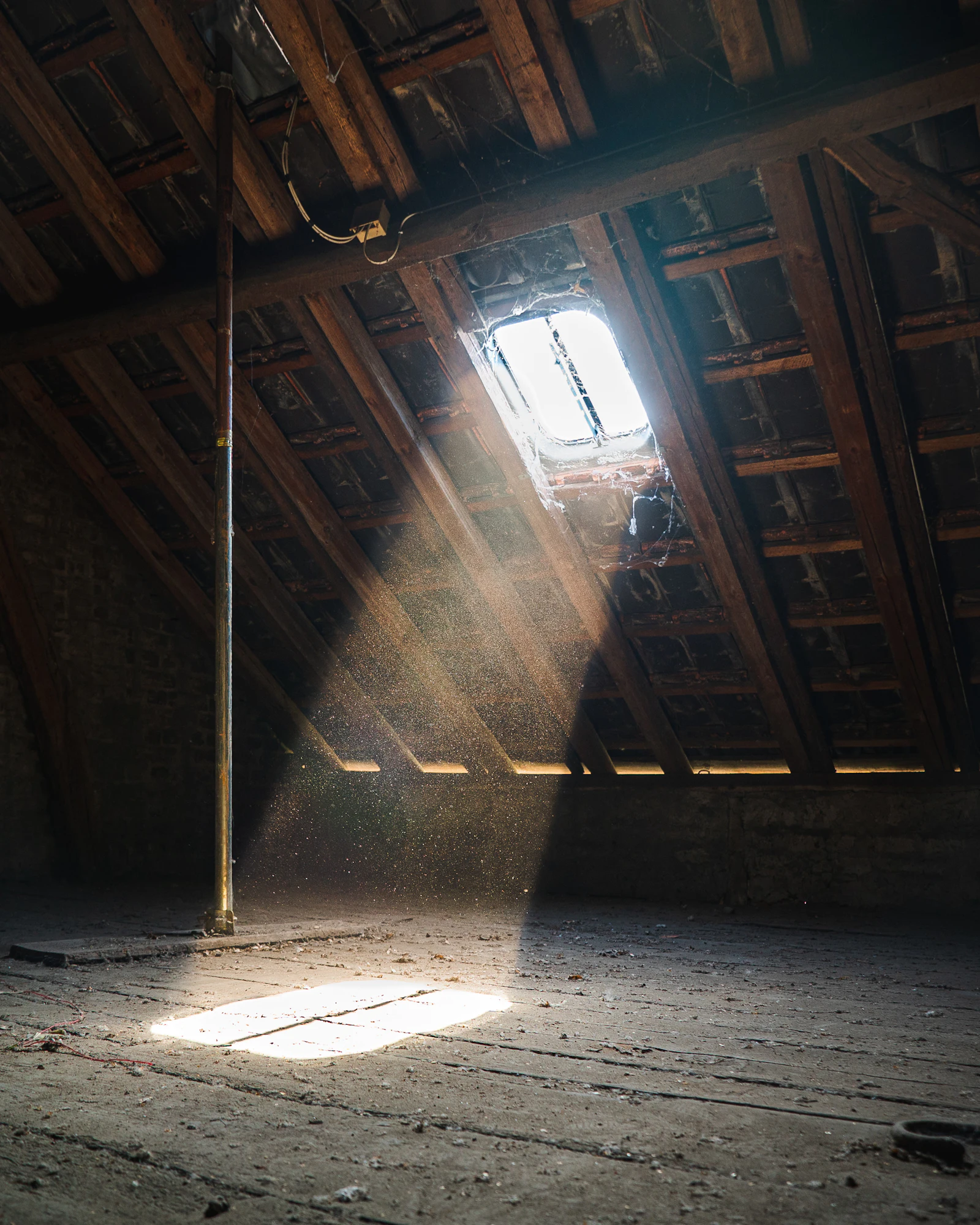 Combles sous charpente en bois traversés par des rayons de soleil