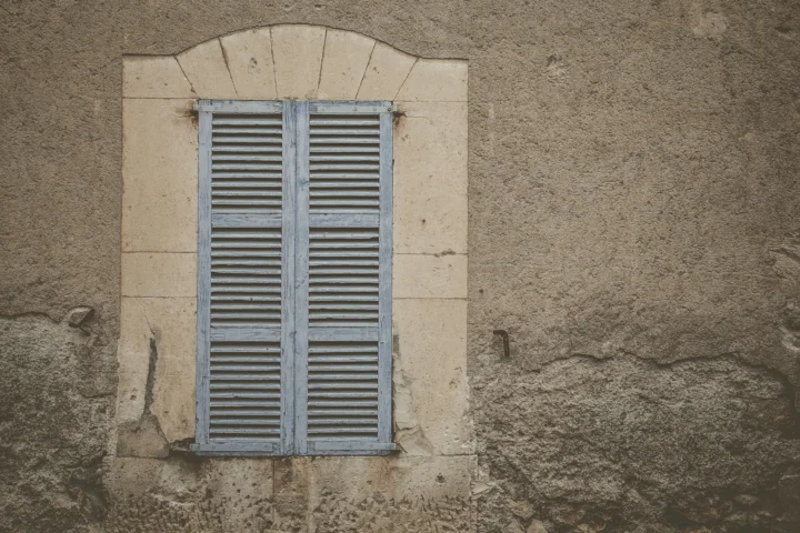 Fenêtre dans un mur ancien avec un volet battant peint en bleu