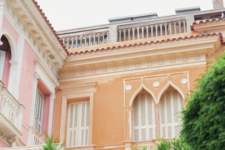 Immeuble aux façades rose et blanche avec balcon en ferronnerie