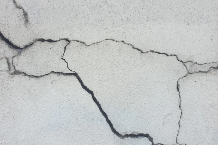 Surface de mur enduit parcourue de fines fissures