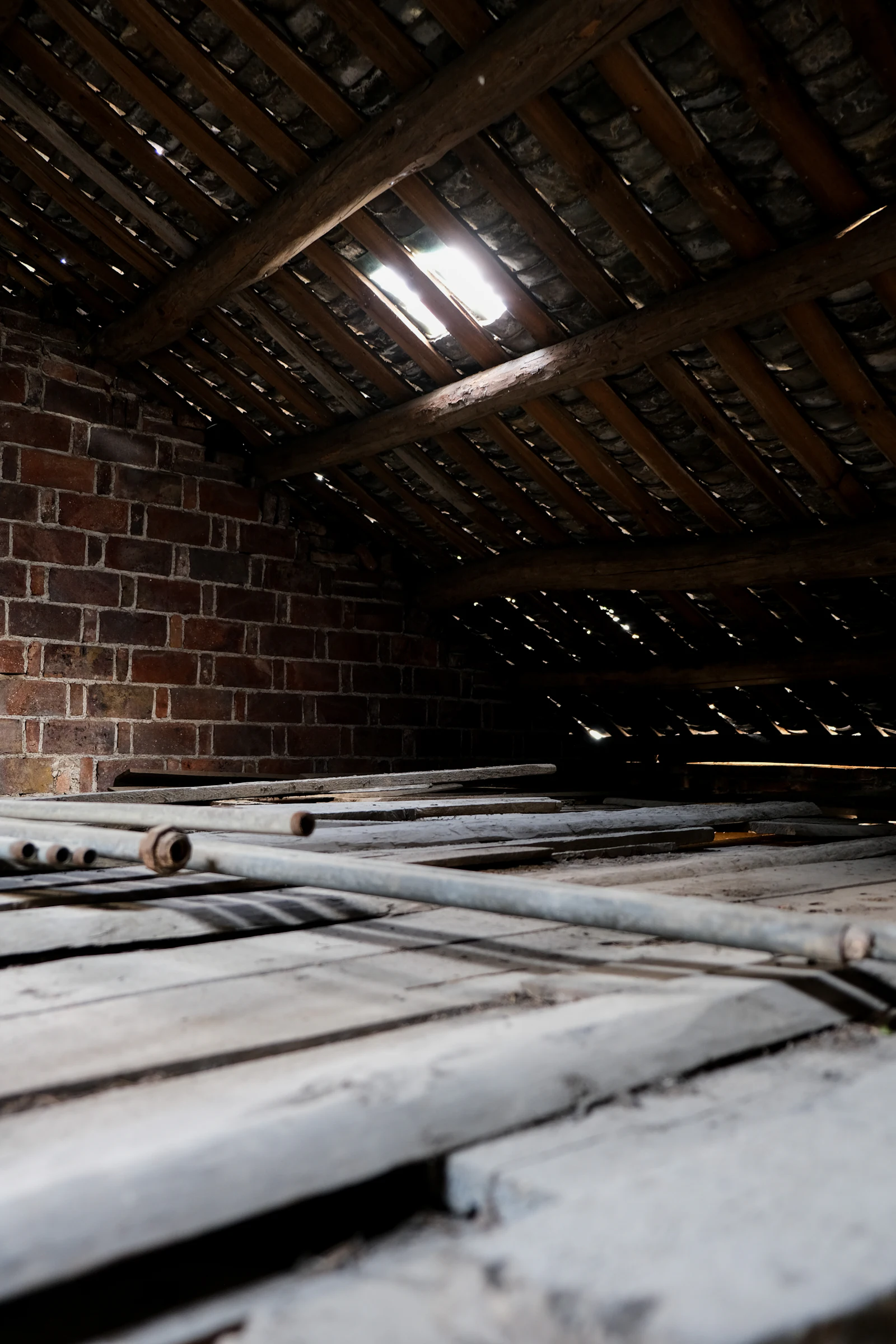 Plancher en bois poussiéreux dans un grenier au mur de briques