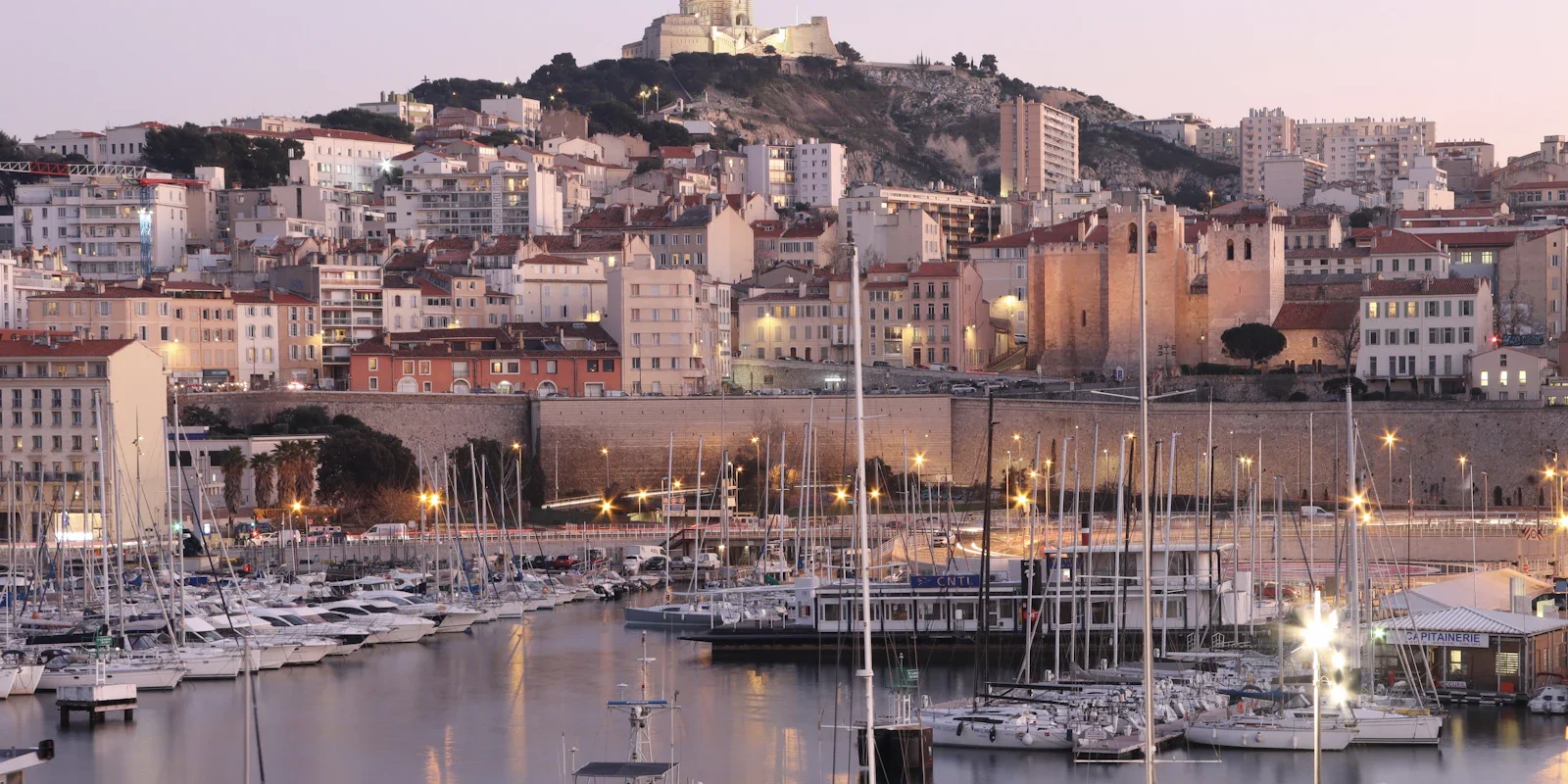 Port de Marseille rempli de bateaux, avec les immeubles de la ville en arrière-plan