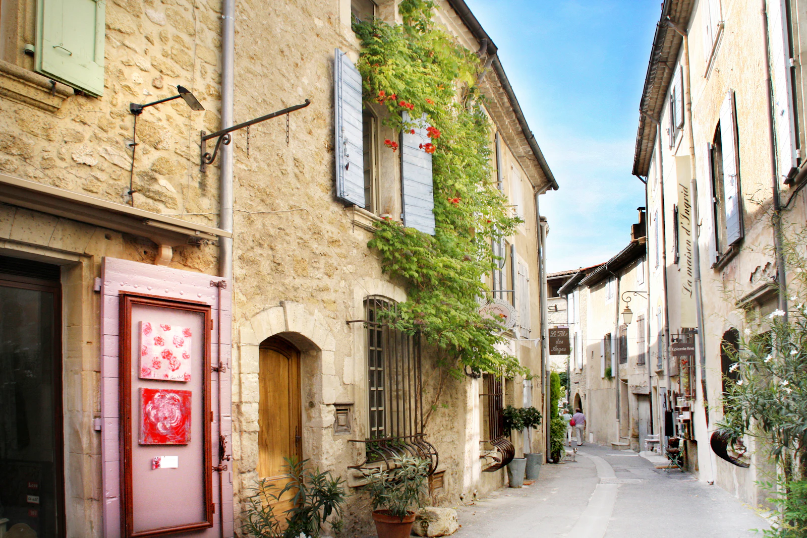 Rue de village provençal bordée de maisons en pierre aux volets clairs
