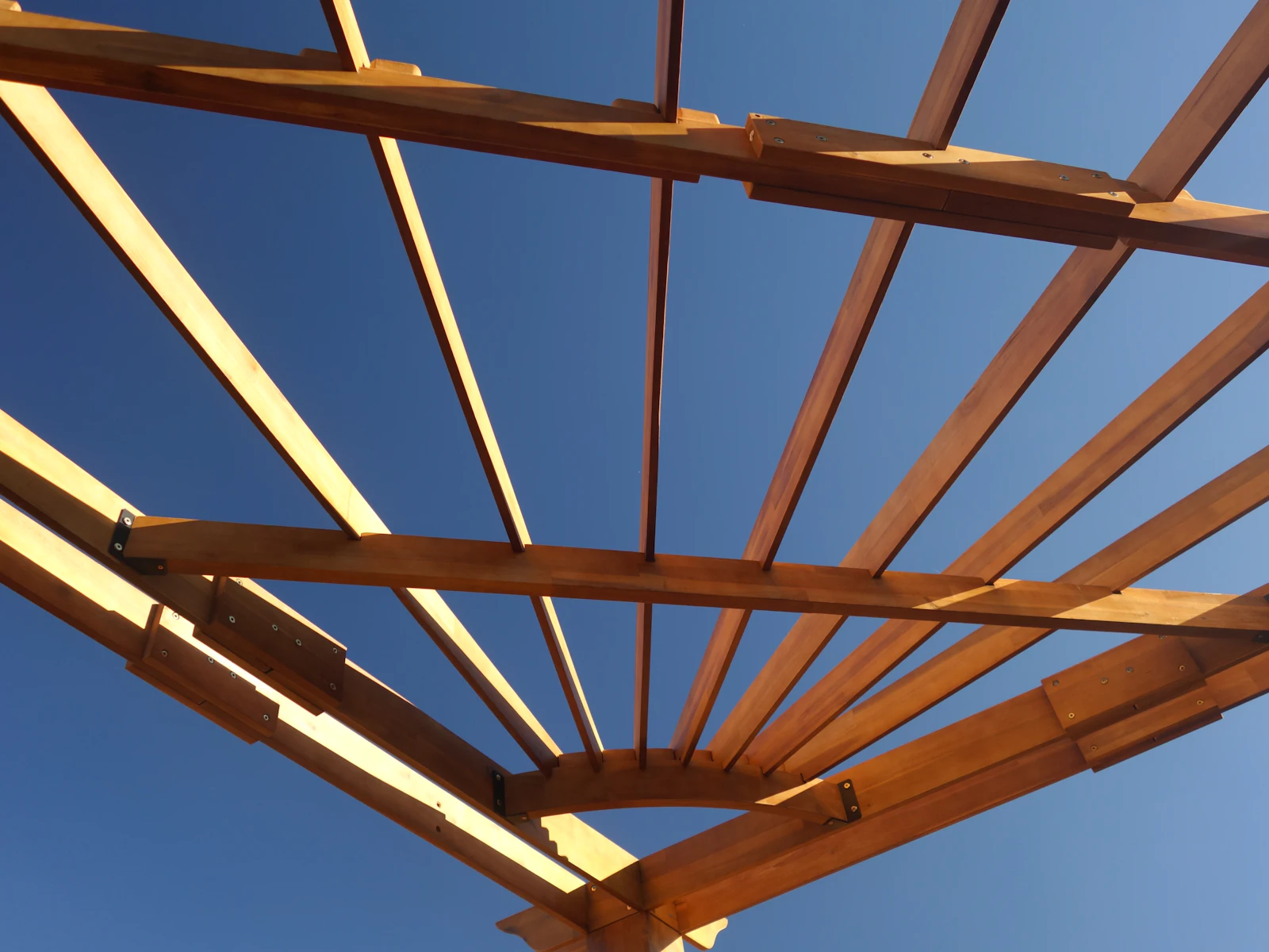 Structure de pergola en bois vue du dessous sur fond de ciel bleu