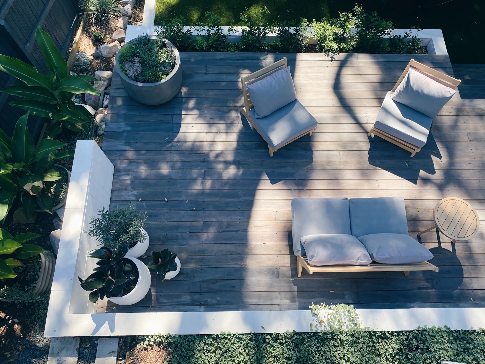 Vue plongeante sur une terrasse en bois avec mobilier et plantes en pots