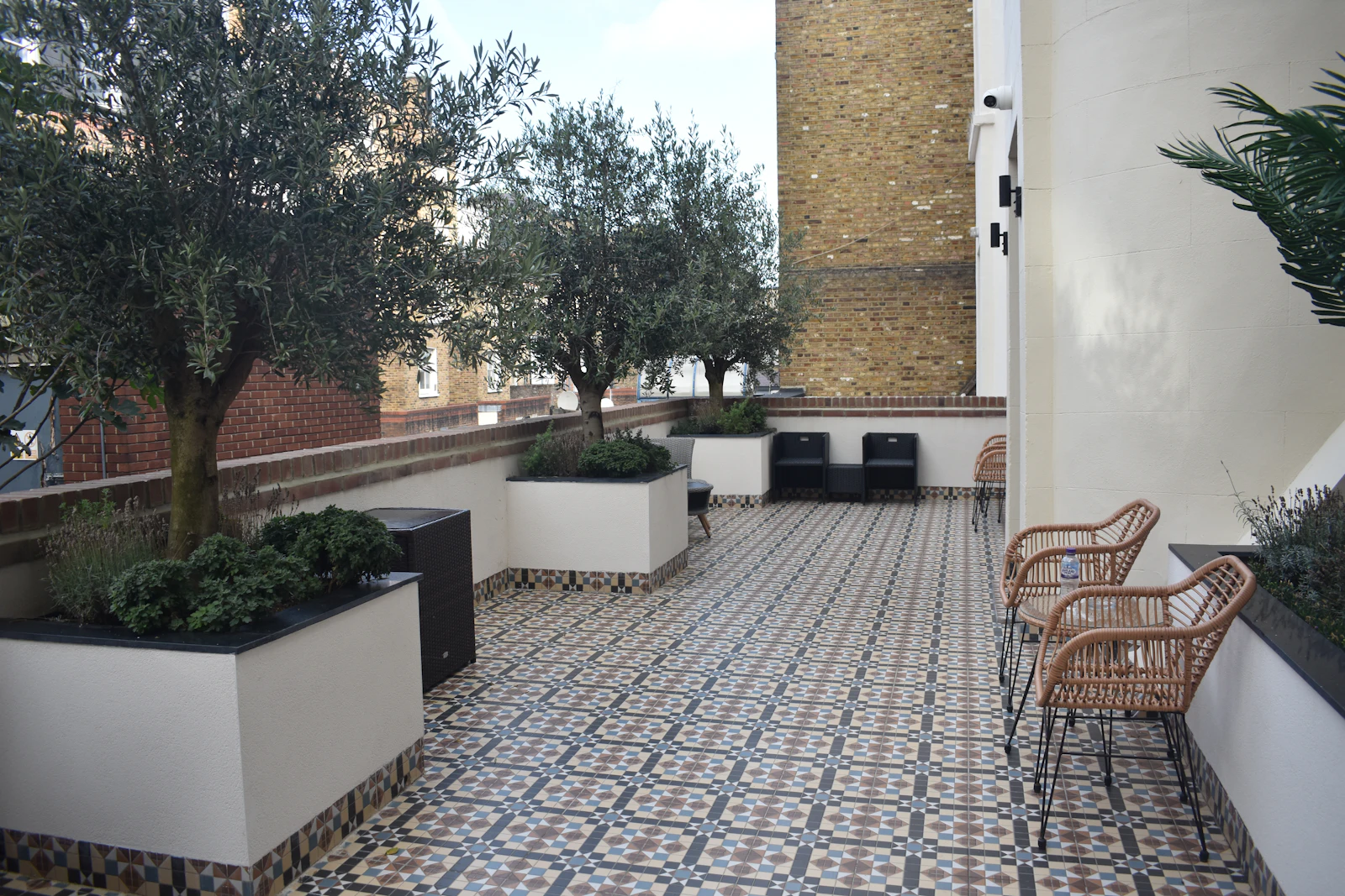 Terrasse carrelée bordée d'arbustes en pots