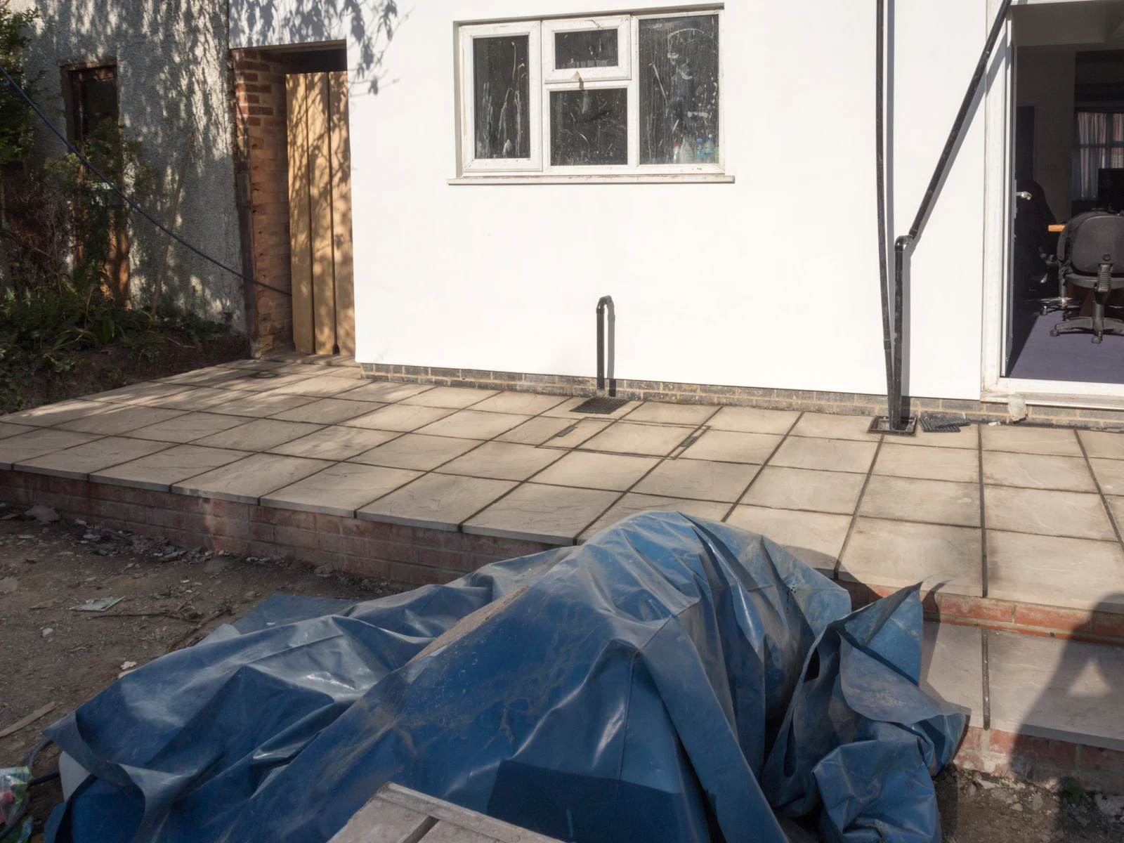 Terrasse dallée en cours de finition devant une maison blanche en travaux
